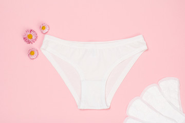 Beautiful women's panties with a sanitary napkins on pink background.