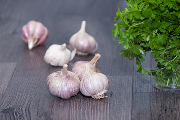 garlic cloves and bulb with bunch of fresh parsley on a wooden background