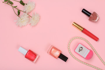 Box with ring and women cosmetics on a pink background.