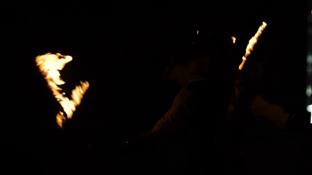 actors in masked women rotate torches at night