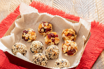 Set of handmade energy balls are lying in cardboard box on red napkin on wooden table.