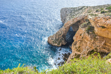 Famous natural limestone arch of the Blue Grotto is a number of sea caverns on the south coast of Malta. The water mirroring showing numerous shades of blue and phosphorescent colours of the flora Blu