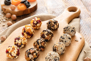 Homemade energy balls are lying in rows on kitchen cutting board on wooden table.
