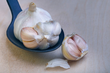 a few slices and cloves of garlic in a black spoon on a wooden background