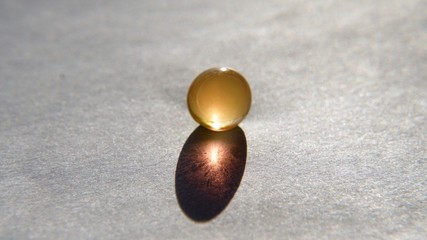 a gel bead with a gold shadow on a white background