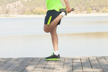 Obraz premium Athletic runner doing stretching exercise, preparing for morning workout in the park 