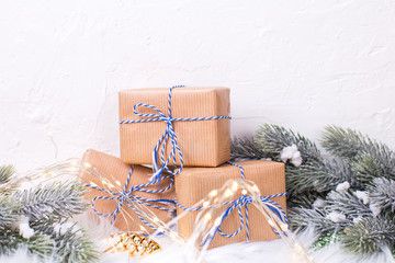 Fototapeta na wymiar Wrapped boxes with presents, fir tree branches and fairy lights on white textured background.