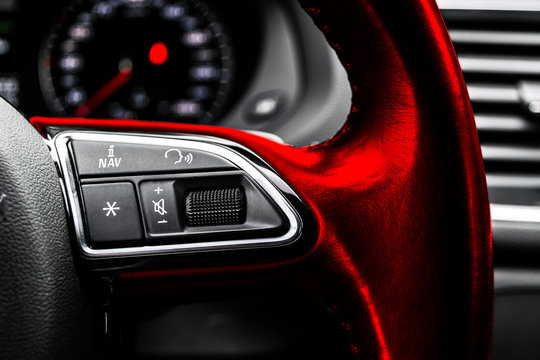 Modern car interior. Red Steering wheel with media phone control buttons, navigation multimedia system background. Car interior details. Car detailing