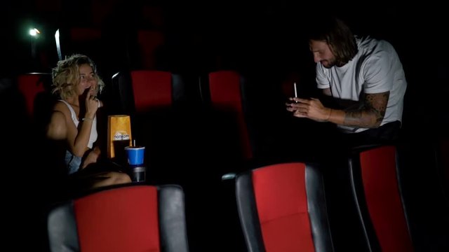 guy photographs a girl in the cinema.