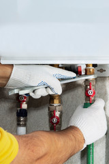 A plumber attaches to a gas pipe boiler with a wrench
