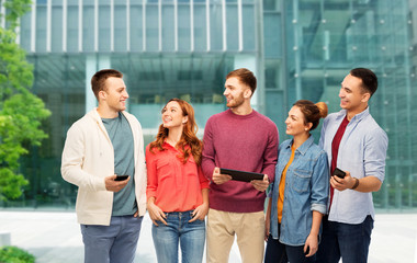 Obraz premium technology, education and people concept - group of smiling friends or students with smartphones and tablet computer over university background