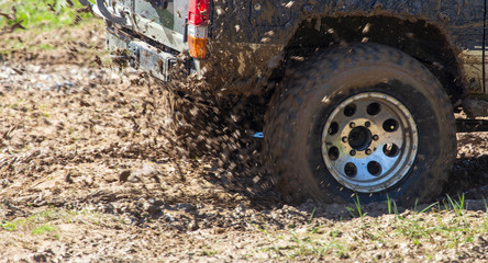 Soil and dirt flies out from under the wheels of a car