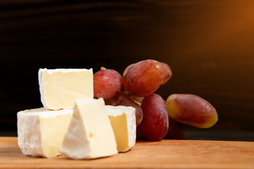 Cheese and grapes on a dark background