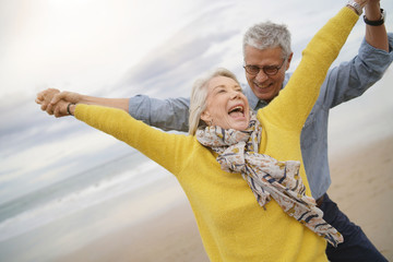  Lively senior couple playing around on beach together