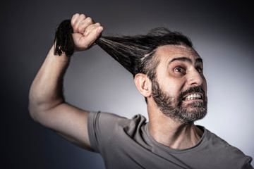  Caucasian man pulling his long hair, concept of anger and madness, resentment and mental disorder.