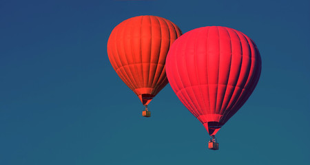 Two Red balloons in the sky. Aerostat. People in the basket. Fun. Summer entertainment. Romantic adventures. Modern toned photo.