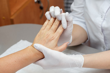 Massage therapist massaging hands of a woman in a beauty salon