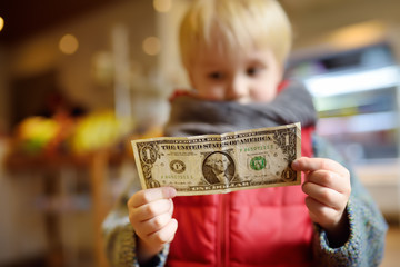 Little boy holds a one-dollar currency note.