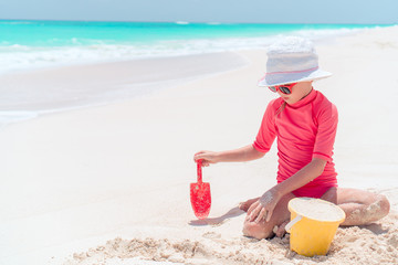 Adorable little girl playing with beach toys during tropical vacation