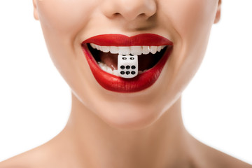 cropped shot of young woman holding dice in teeth isolated on white