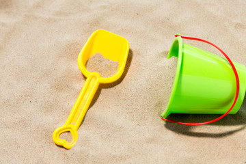 Fototapeta na wymiar toys, childhood and summer concept - close up of bucket and shovel on beach sand