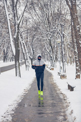 Man jogging in a cold winter snowy day outdoors.