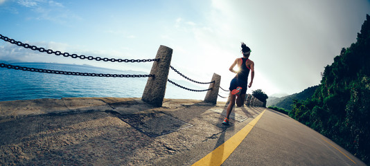 young fitness woman runner running on sunrise seaside road