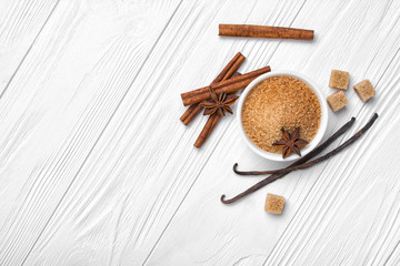 Top view of brown cinnamon granulated and cane cubes sugar with spices on white wooden background