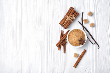 Top view of brown cinnamon granulated and cane cubes sugar with spices on white wooden background