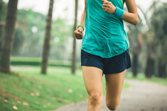 Young fitness sportswoman runner running on tropical park trail