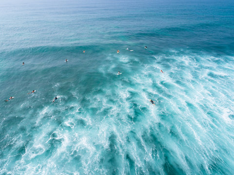 Aerial view from drone of surfers paddling for catching waves during surfing in the indian ocean