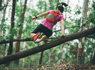 Sportswoman cross country trail running in forest