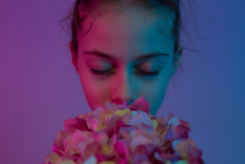 Child girl smelling the flowers with closed eyes - dreamlike mood.