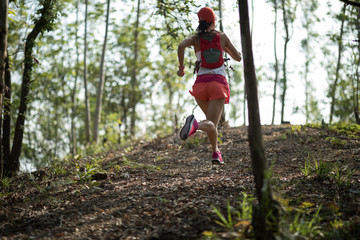 Sportswoman cross country trail running in forest