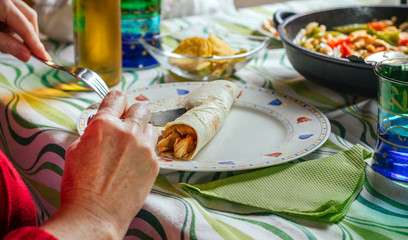 Detail of woman rolling mexican fajita on the plate