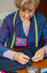 Senior female seamstress sewing cloth to make a garment in her workshop