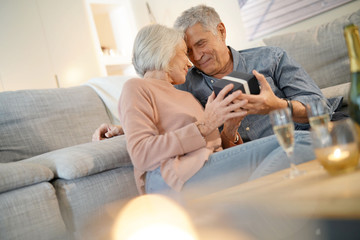 Obraz premium Modern senior couple exchanging gifts at home