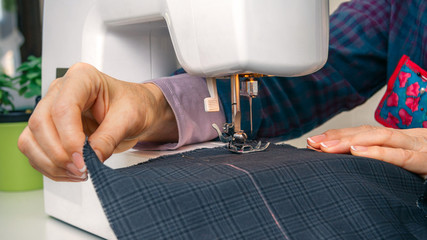 Closeup of seamstress hands working with clothing item on a sewing machine