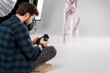 photographer sitting with camera and young model posing in photo studio