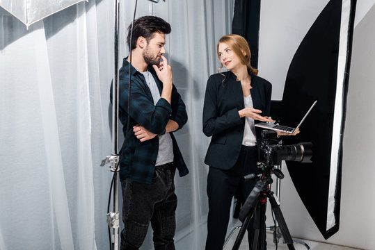 photographer and model using laptop and smiling each other in studio