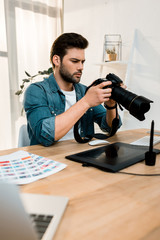 handsome young photographer using camera at workplace