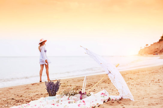 Picnic, relaxing on a wild beach and a blurred silhouette of a girl strolling along the beach in the background. Vintage style photo.
