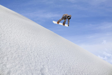 Naklejka na ściany i meble Snowboarder flying on the background of snowy slope. Extreme winter sports, snowboarding. Copy space.