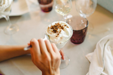 Woman's hands tasting and enjoying a cold dessert in a glass.