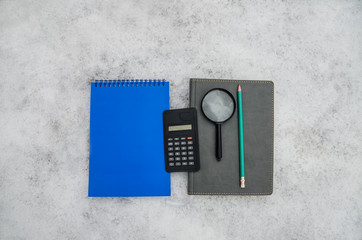 Blue and gray notebooks, pencil, calculator, magnifier against the background of snow