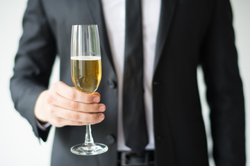 Closeup of business man holding goblet with champagne. Person celebrating event. Holiday concept. Isolated cropped front view on white background.