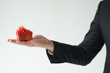 Closeup of business man holding small gift box. Person greeting someone. Gift concept. Isolated cropped view on white background.