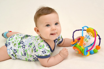 The amusing baby holds a toy lying on a stomach