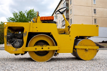 yellow old road roller in the yard of the house make sidewalks