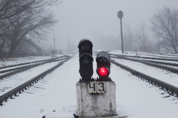 Semaphore on the railway in winter, glowing yellow. Gloomy scene